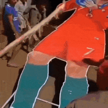 a man in a red shirt and blue socks is standing next to a rope .