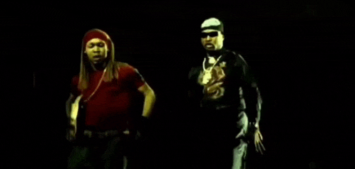 a man in a red shirt and a man in a black shirt are dancing in a dark room .