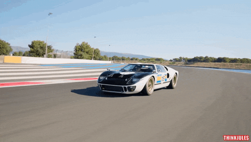 a black and white race car with the number 155 on the side is driving down a track
