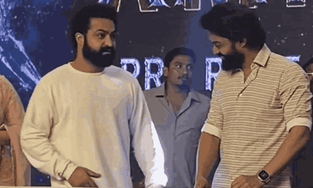 two men with beards are standing next to each other in front of a sign that says prf