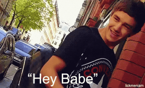 a young man leaning against a brick wall with the words hey babe below him