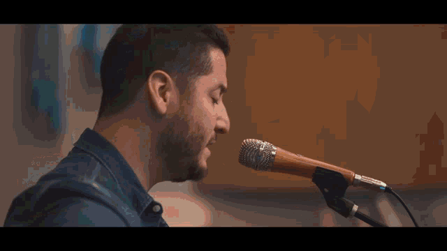 a man is singing into a microphone while playing a guitar