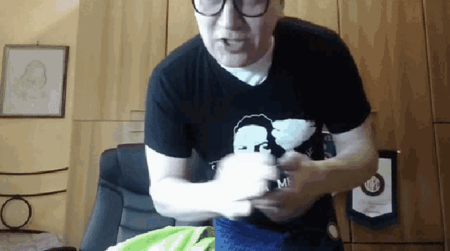 a man wearing glasses and a black shirt with a picture of a man with the word mi on it