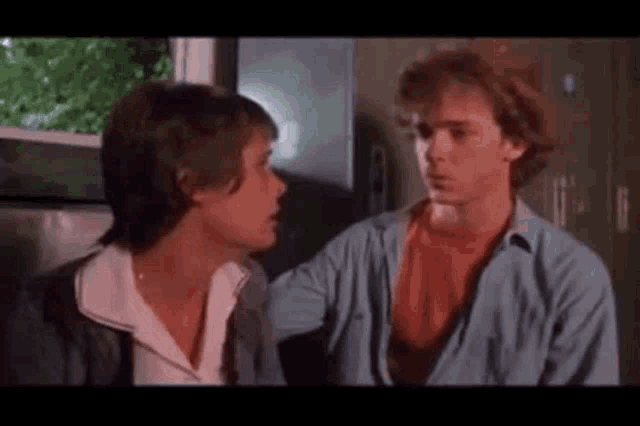 two men are talking to each other in a room .