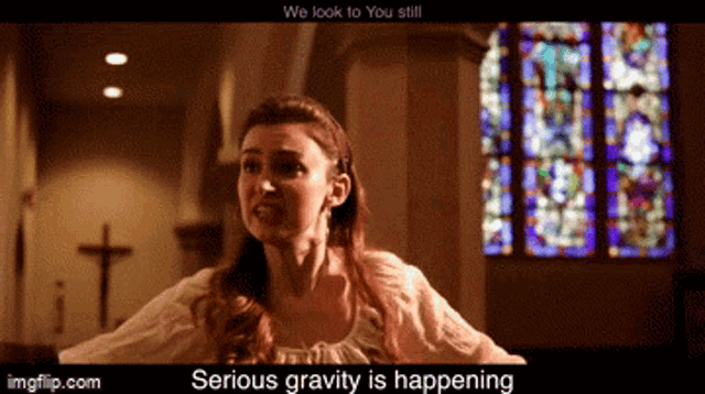 a woman is standing in front of a stained glass window in a church and says serious gravity is happening