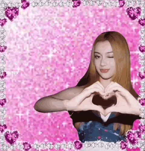 a girl is making a heart shape with her hands on a pink background .
