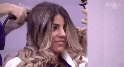 a woman is getting her hair curled with a hair dryer .