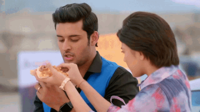 a man and a woman are eating a pizza together