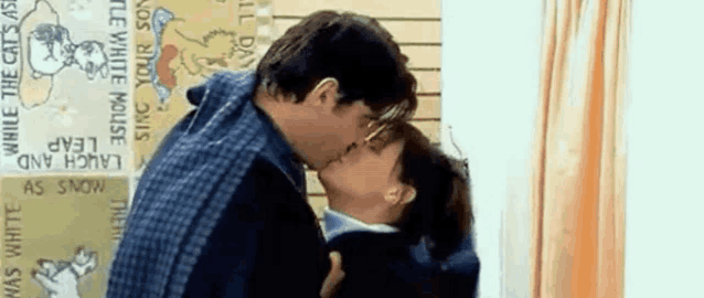 a man and a woman are kissing in front of a sign that says laugh and leap while the cats ask .
