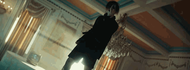 a woman in a black dress is standing in a room with a chandelier ..