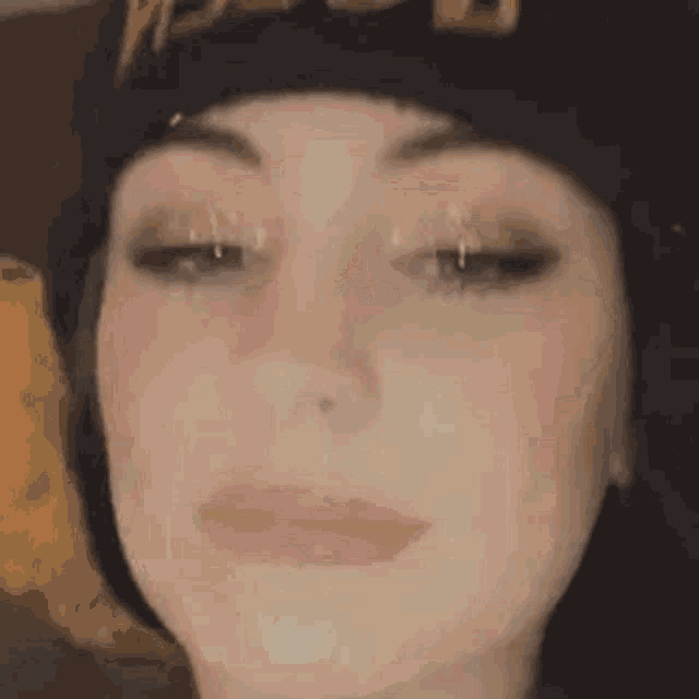 a close up of a woman 's face wearing a beanie and making a funny face .