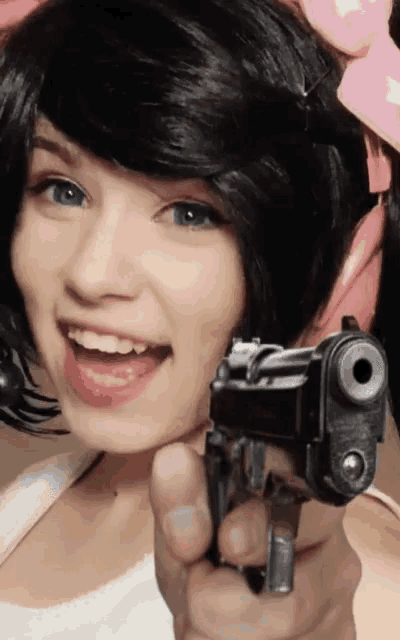 a woman is pointing a gun at the camera with her mouth open