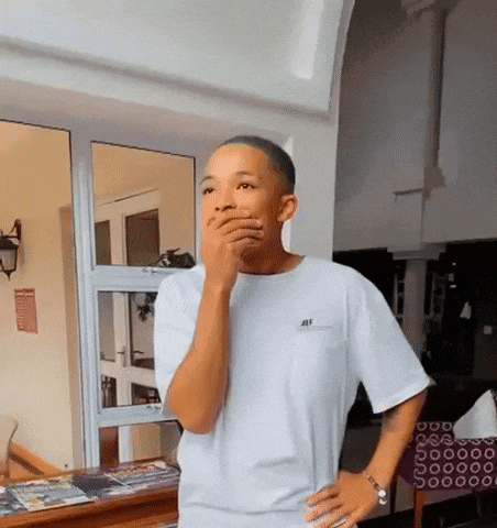 a man in a white t-shirt is covering his mouth