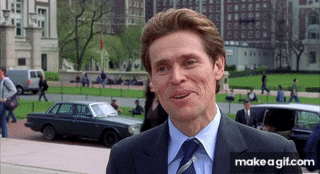 a man in a suit and tie stands in front of a parked car