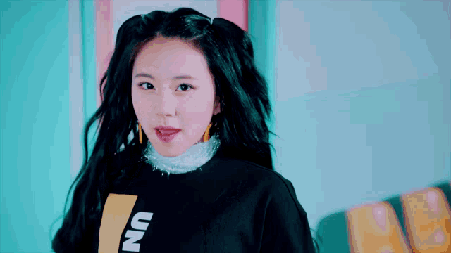 a woman with pigtails is wearing a black sweatshirt with the word un on it .
