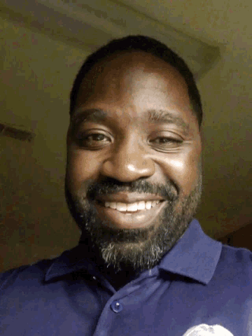 a man with a beard and a blue shirt smiles for the camera