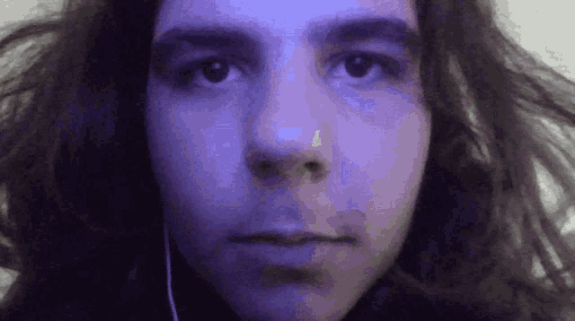 a close up of a man 's face with long hair and a purple background