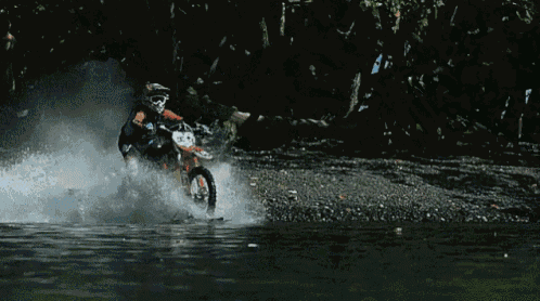 a person is riding a dirt bike in the water with the number 23 on the front