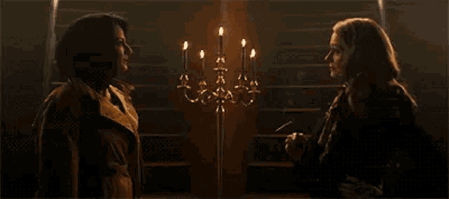 a couple of women are standing next to each other in front of a candelabra .