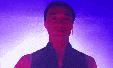 a close up of a man 's face with a purple light behind him
