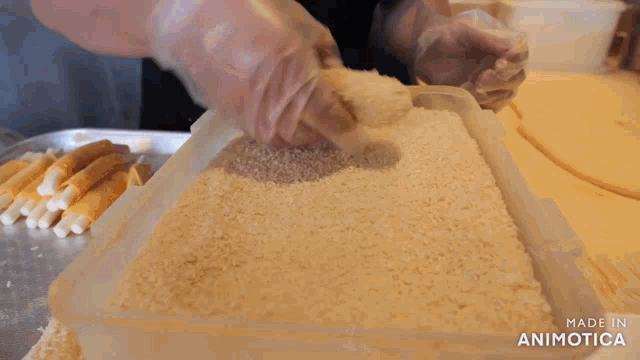 a person is spreading bread crumbs in a plastic container made in animatica