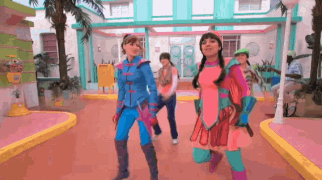 a group of girls are dancing in front of a building with a yellow mailbox in the background