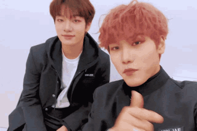a young man with red hair is giving a thumbs up next to another young man