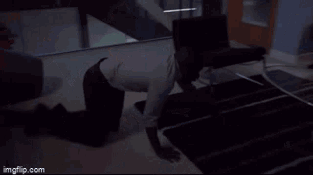a man in a white shirt is standing in front of a microwave with a knife in his hand .