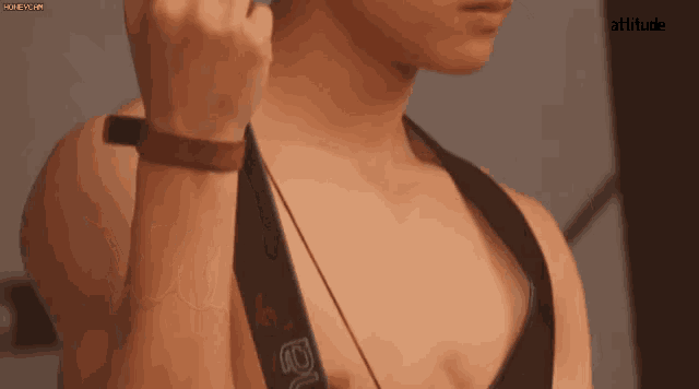 a man without a shirt is standing in front of a mirror and adjusting his straps .