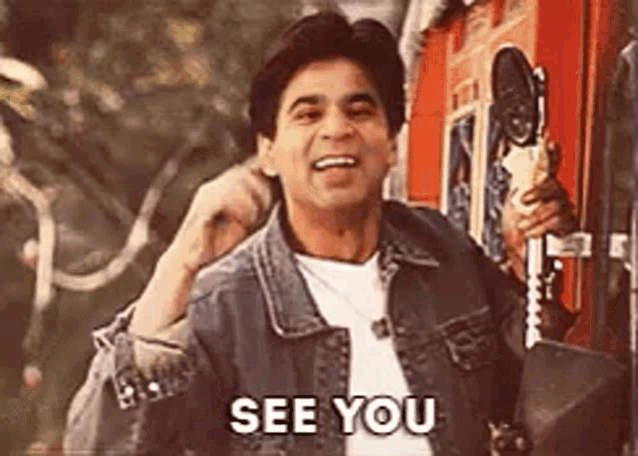 a man in a denim jacket is saying `` see you '' while holding a telephone .