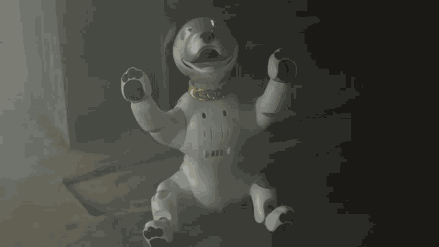 a white robotic dog with a gold collar is sitting on the ground