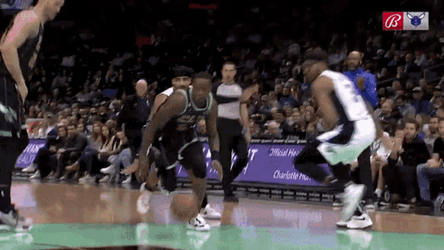 a basketball game is being played in front of a crowd with the letter b on the bottom right