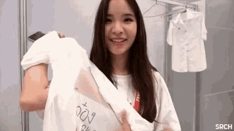 a woman is holding a white shirt that says ' srch ' on it