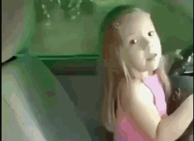 a little girl in a pink dress is sitting in a car