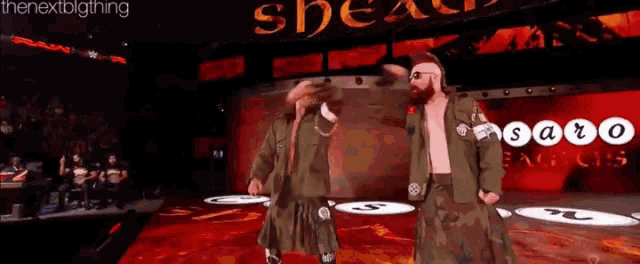 two men in kilts are dancing on a stage in front of a sign that says saro
