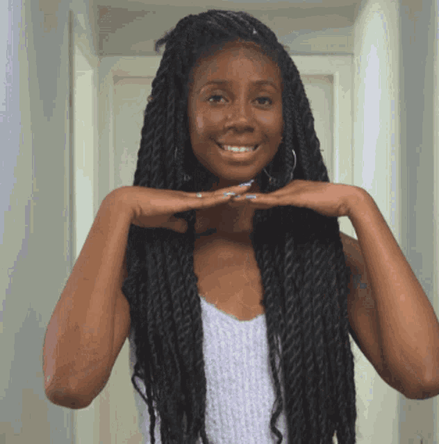 a woman with braids on her hair is smiling and holding her hands to her face