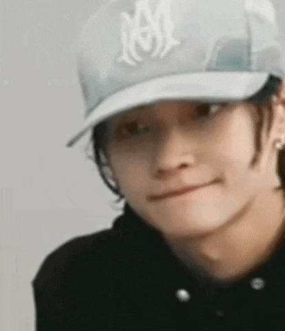 a young man wearing a baseball cap and a black shirt is making a funny face .