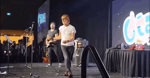 a man is standing on a stage playing a guitar .