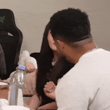 a man and woman are kissing while sitting at a table .