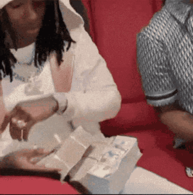 a man and a woman are sitting at a table with a pile of money in front of them