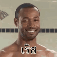 a shirtless man is smiling in a shower while standing in front of a shower head .
