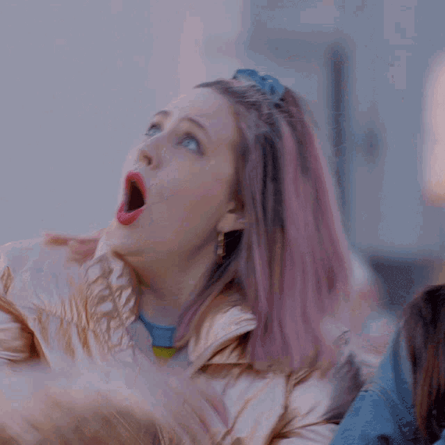 a woman with pink hair and a tattoo on her hand is blowing a kiss