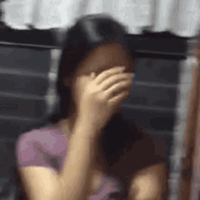 a woman is covering her face with her hand while sitting in a chair .