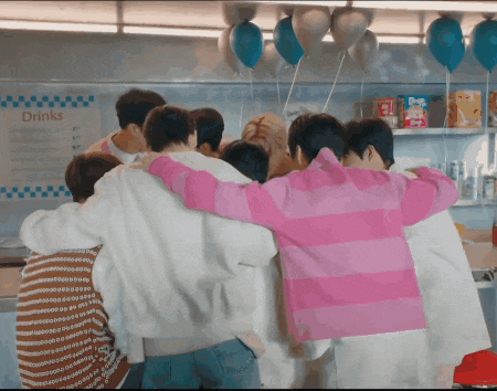 a group of people hugging each other in front of a drinks menu