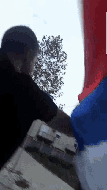 a man in a black shirt is holding a blue and red flag
