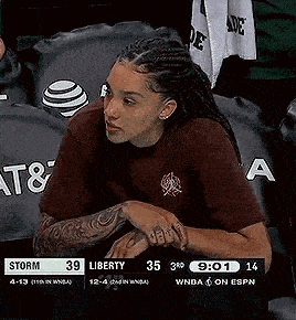 a woman is sitting in the stands during a basketball game .