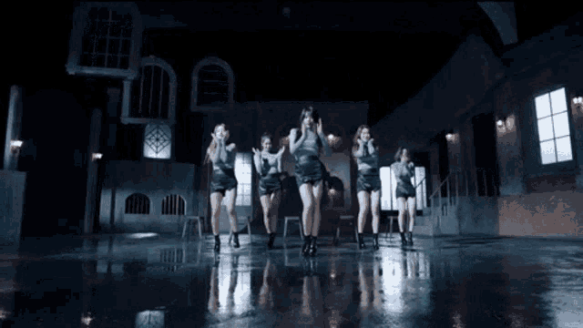 a group of women are dancing in a dark room with windows