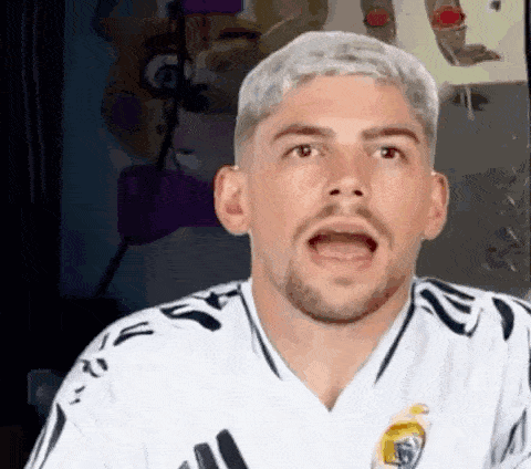 a man with a beard and a white shirt is making a surprised face .