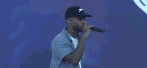 a man is singing into a microphone in front of a blue background with a heart .