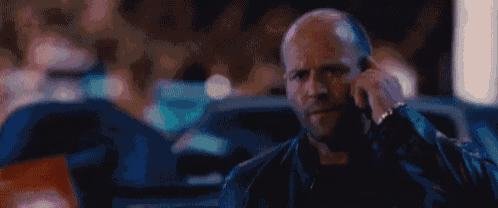 a bald man is talking on a cell phone in a dark room .